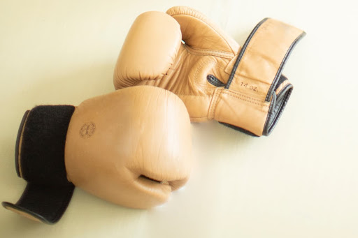 Imagem de mãos usando luvas para isolação elétrica, um alicate e fio